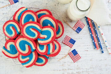 4th of July Holiday background. Red white and blue pinwheel sugar cookies with milk glass for July...