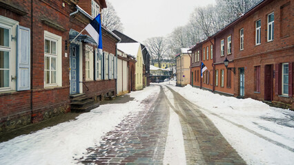 This is one of the most beautiful streets in Tartu Estonia, it is winter and there is snow on the ground and on the brick houses, the cars that have passed through the street leave marks on the ground