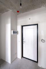 The entrance hall of the new apartment is not renovated. View of the front door