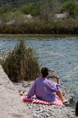 vertical video of an unrecognisable girl with her back turned in a lilac shirt sitting on a ledge...