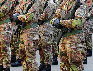 squad of soldiers in green and brown camouflage uniforms black gloves and assault rifles in hands