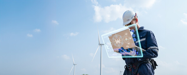 engineer working on site in wind turbine farm with clear blue sky on the background. Alternative...