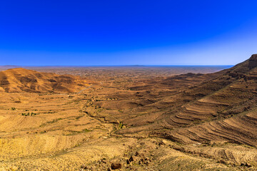 Widok na skaliste góry Dahar, tapeta. Niebieski kolor nieba i palące słońce, skała, kamień, górski krajobraz, egzotyczny kraj, Tunezja