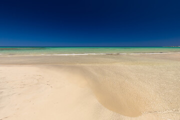 Krajobraz morski, piaszczysta plaża i wybrzeże, żółty piasek, widok na lazurowe morze, niebieski kolor nieba, wyspa Djerba, Tunezja. Tapeta, egzotyczne tło © anettastar
