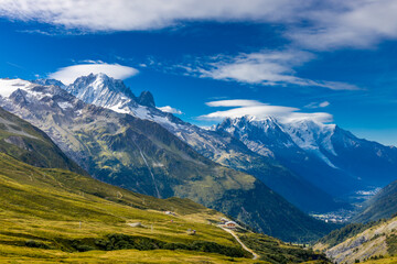 Tour du Montblanc beautiful mountain ladscapes of the Alps green valley, snow summit of Montblanc and rocky peaks of Aiguille du Midi in summer sunny weather blue sky, trekking and hiking in Chamonix