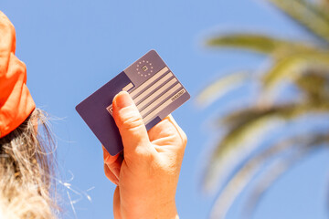 European health insurance card held in hand against the background of holiday sky and palm trees,...