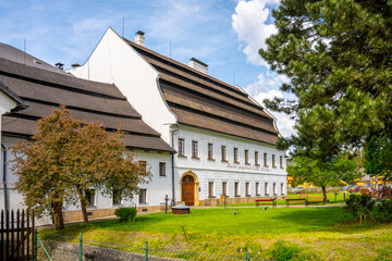 A white building with a distinctive roof, part of a historic paper mill in Velke Losiny, Czechia.