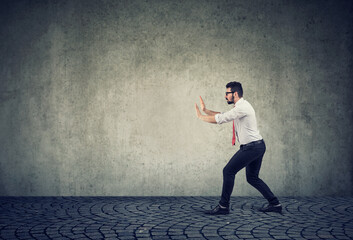 Business man pushing invisible obstacle 