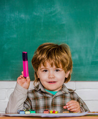 Kid is learning in class on background of blackboard. Preschooler near the blackboard. Young...