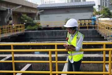 Workers under checking the wastewater treatment pond industry to control the water support...