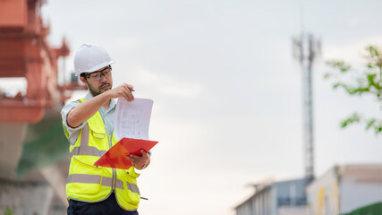 An Asian male engineer works at a motorway bridge construction site,Civil worker inspecting work on crossing construction,Supervisor working at high-speed railway construction site