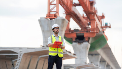 An Asian male engineer works at a motorway bridge construction site,Civil worker inspecting work on...