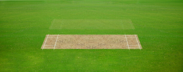 A cricket pitch direct top view of the layout with the grass cricket field. The pitch is inside the field and green field, Cricket match between two teams.