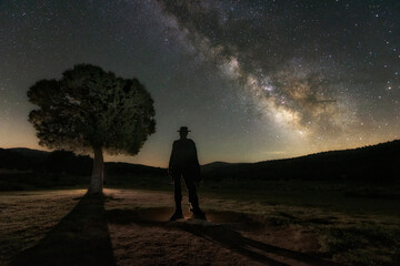 Cowboy silhouette looks towards the Milky Way on a starry night at Sad Hill Cemetery, film location - Powered by Adobe