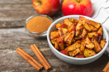 Apples with cinnamon on a textured wooden background. Fragrant red spiced apples with cinnamon sticks and star anise. Apple slices with spicy spices. Place for text. Copy space. Harvesting. Fruits.