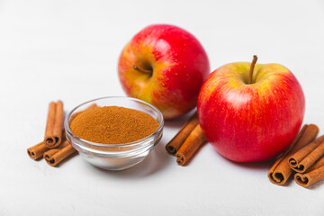 Apples with cinnamon on a textured wooden background. Fragrant red spiced apples with cinnamon sticks and star anise. Apple slices with spicy spices. Place for text. Copy space. Harvesting. Fruits.