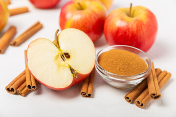 Apples with cinnamon on a textured wooden background. Fragrant red spiced apples with cinnamon sticks and star anise. Apple slices with spicy spices. Place for text. Copy space. Harvesting. Fruits.