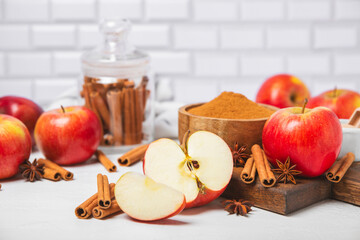 Apples with cinnamon on a textured wooden background. Fragrant red spiced apples with cinnamon sticks and star anise. Apple slices with spicy spices. Place for text. Copy space. Harvesting. Fruits.