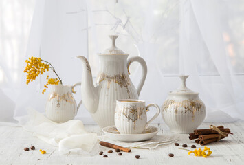 Modern still life with a coffee set and a spring mimosa branch on a light windowsill