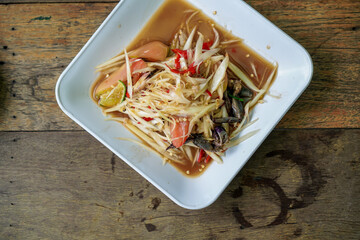 Thai food papaya salad with cabbage yard long bean on white plate , papaya salad with crab and fermented fish. Thai papaya salad or Som tum. The famous local Thai street food with hot and spicy