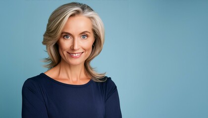 Obraz premium Close up of a confident beautiful middle aged businesswoman in a dark blue top, smiling isolated on blue background, space for text.