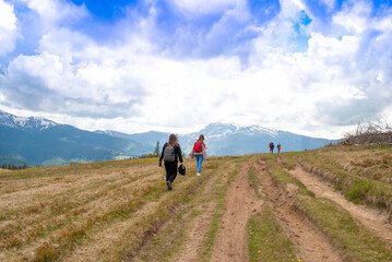 A group of tourists rises to the mountains. Young people with backpacks travel. Picturesque mountain landscape, tracking, tourism, travel