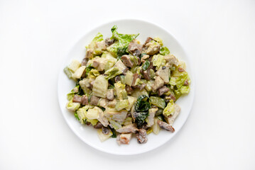 Salad with herbs and meat on a white plate. Delicious salad with mayonnaise and mushrooms.