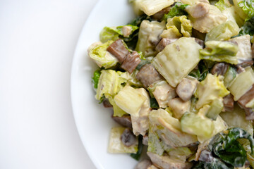 Salad with herbs and meat on a white plate. Delicious salad with mayonnaise and mushrooms.