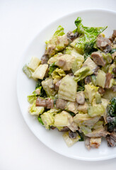 Salad with herbs and meat on a white plate. Delicious salad with mayonnaise and mushrooms.