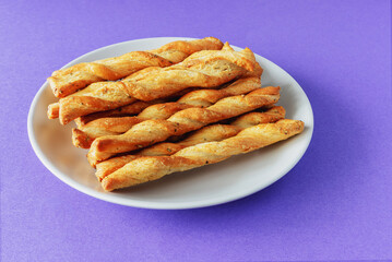 Sticks of buttery yeast dough on a plate on a purple background