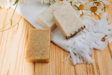 Handmade soap from natural ingredients, various herbs, chamomile. Concept of sustainable use, bath products on a wooden background. Top view