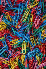 A chaotic yet vibrant array of colored paper clips, filling the entire frame. The paper clips come in bright shades of red, blue, green, yellow, and purple, creating a lively and dynamic background. 