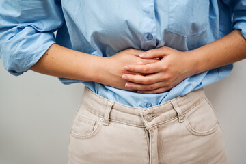 Woman Holds Her Aching Belly With Both Hands. Suffering From Stomach Pain.