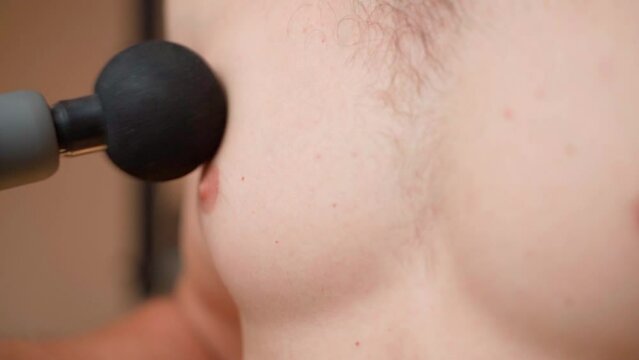 Percussion massage of male breasts close-up. Large round percussion massager head
