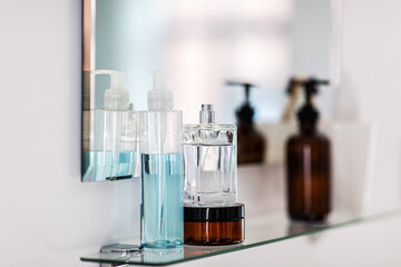 hygiene, beauty and daily routine concept - close up of lotion, perfume and moisturizer on mirror...