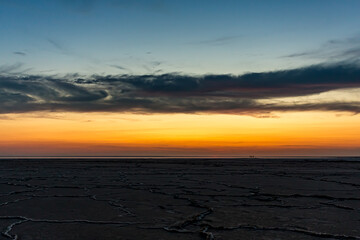 Sunset or sunrise on salt lake Elton (Russia) Tall altocumulus and cirrocumulus clouds against the background of salt marsh and a large amount of brine. Evening or morning.