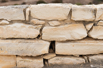 Beige stone wall of ancient city, sand rocks set, texture