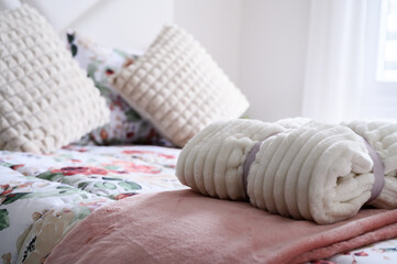Inviting bedroom scene with rolled up comforter and decorative pillows on a floral bed