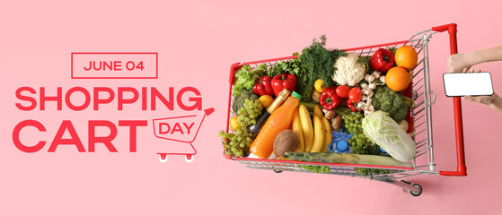 Woman with mobile phone pushing shopping cart full of food on pink background