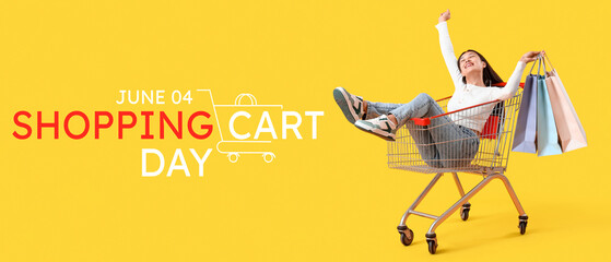 Young Asian woman with bags in shopping cart on yellow background