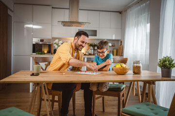 Father and son play board game have fun together at home