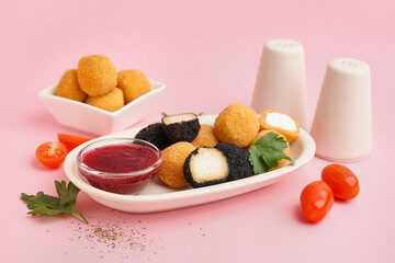 Plate with different delicious fried mozzarella balls, tomatoes and sweet sauce on pink background