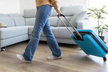 Fototapeta premium girl leaving home with her blue carry-on suitcase to go on a trip 