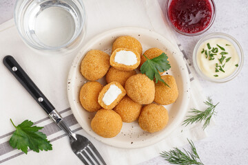 Plate with delicious fried mozzarella balls, sauces and fork on light background