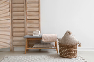 Stack of clean soft towels on soft bench near white wall