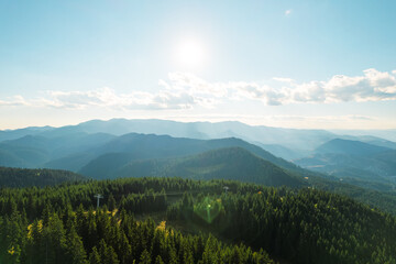 Beautiful mountains range against blue sky on sunny. Green coniferous forest and grass meadows top view aerial view. Nature. Relax. Travel