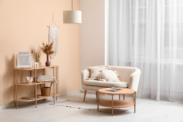 Comfortable sofa with cushions and wooden shelving unit with decor near window in interior of living room