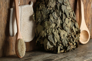 Set of accessories for sauna with birch broom on wooden background, closeup