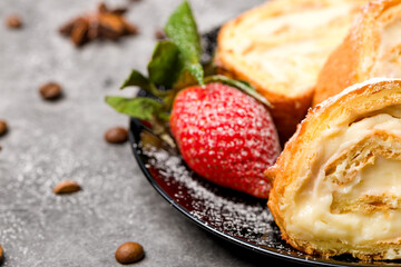 Sliced rolls with custard. The dessert is decorated with fresh strawberries.