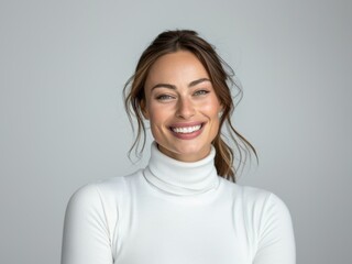 Obraz premium Young brunette woman with a beautiful smile on a gray background. Feminine beauty. Natural smile. Healthy teeth.